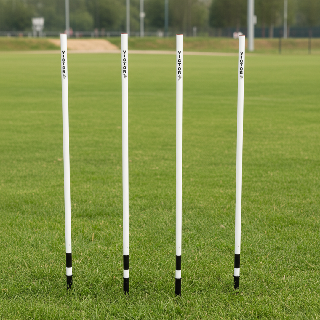 Four white goal posts with black bases on a grass field